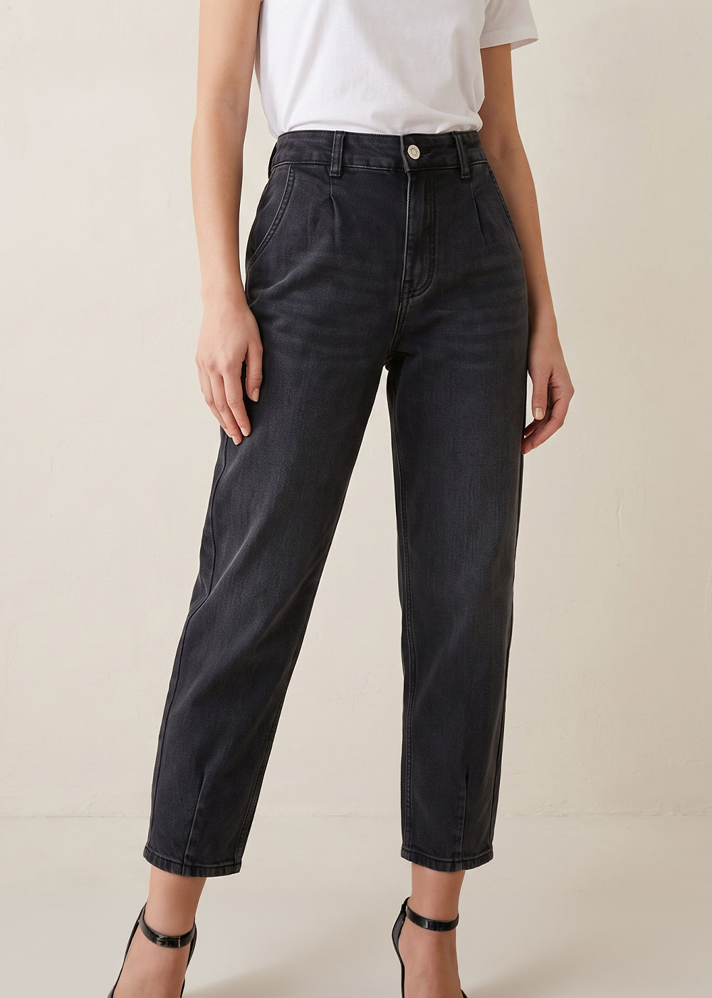 Model wearing high-waisted cropped black washed jeans with white T-shirt and black ankle-strap heels