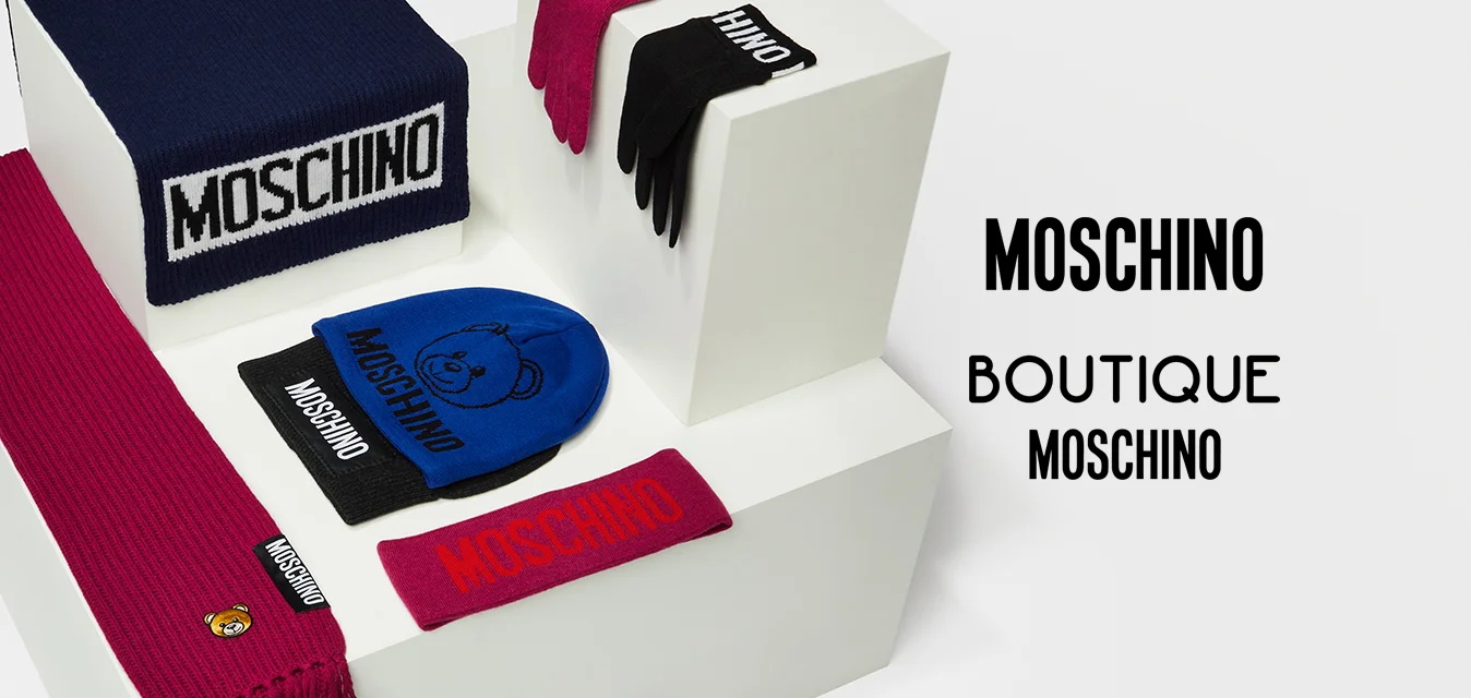 Collezione di accessori Moschino che include un berretto a strisce blu navy, sciarpe rosse e nere, berretto blu e guanti coordinati, tutti con logo.