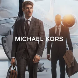 Due uomini in abiti su misura passano accanto a un jet privato. Il primo uomo porta una borsa di pelle marrone, mentre il secondo tiene un cappotto beige.