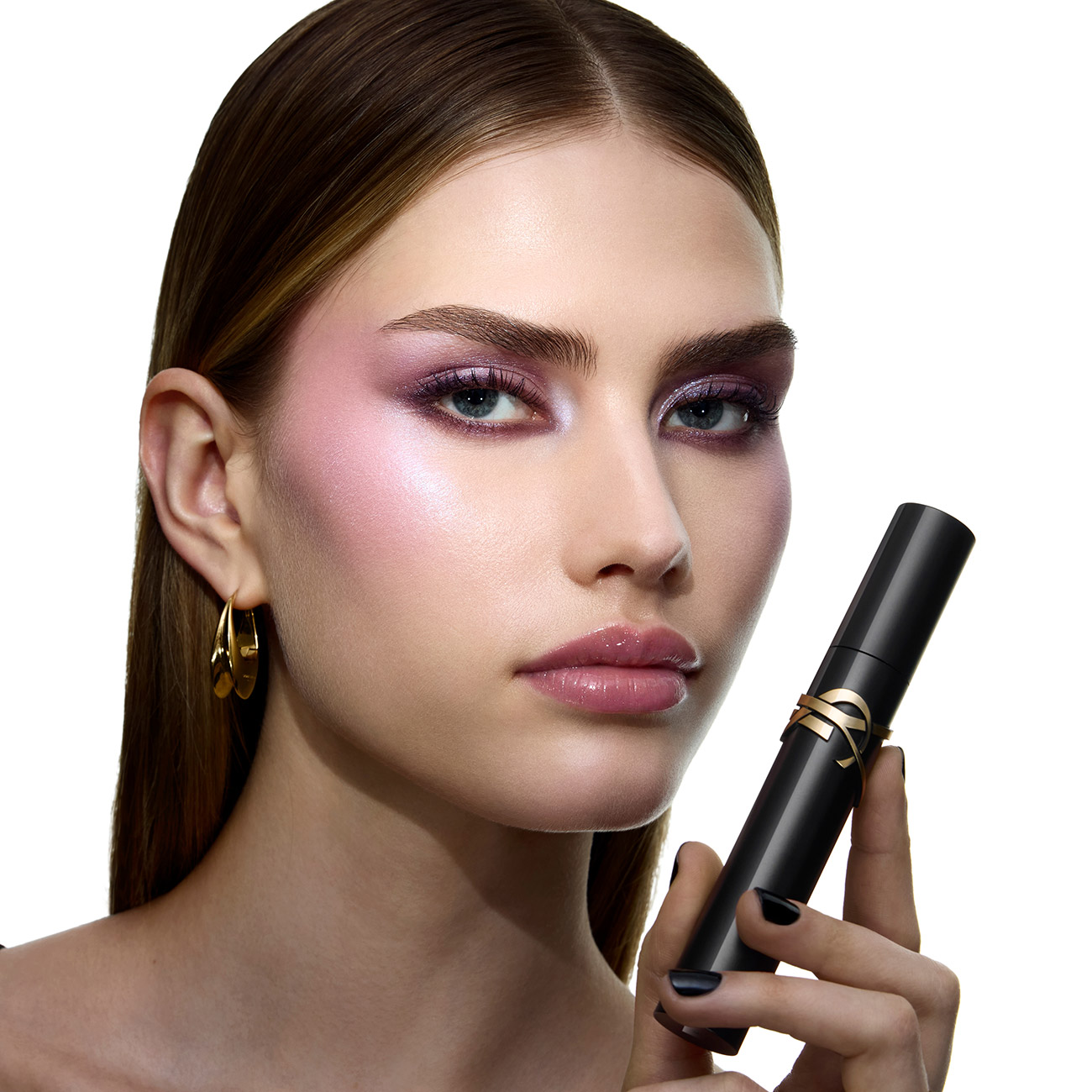 Una donna con un trucco occhi viola brillante che tiene in mano un mascara nero YSL Lash Clash.