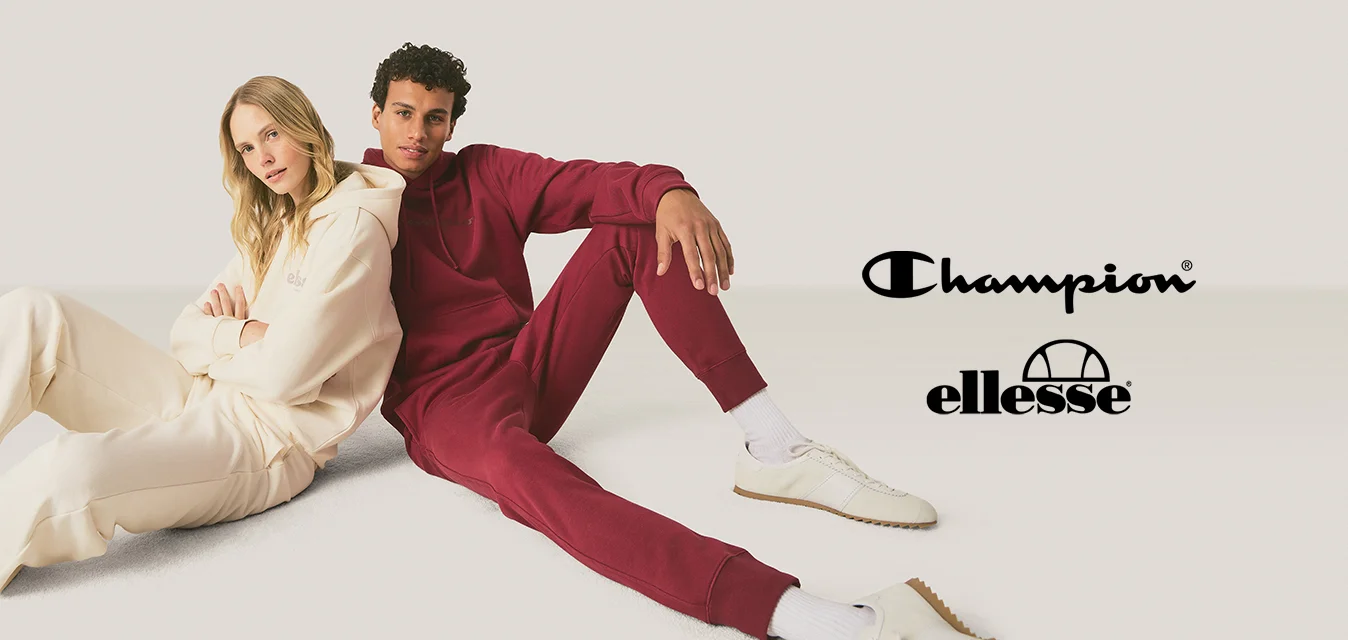 Una donna con abiti casual color crema e un uomo con abiti casual rossi sono seduti sul pavimento contro uno sfondo chiaro e uniforme.