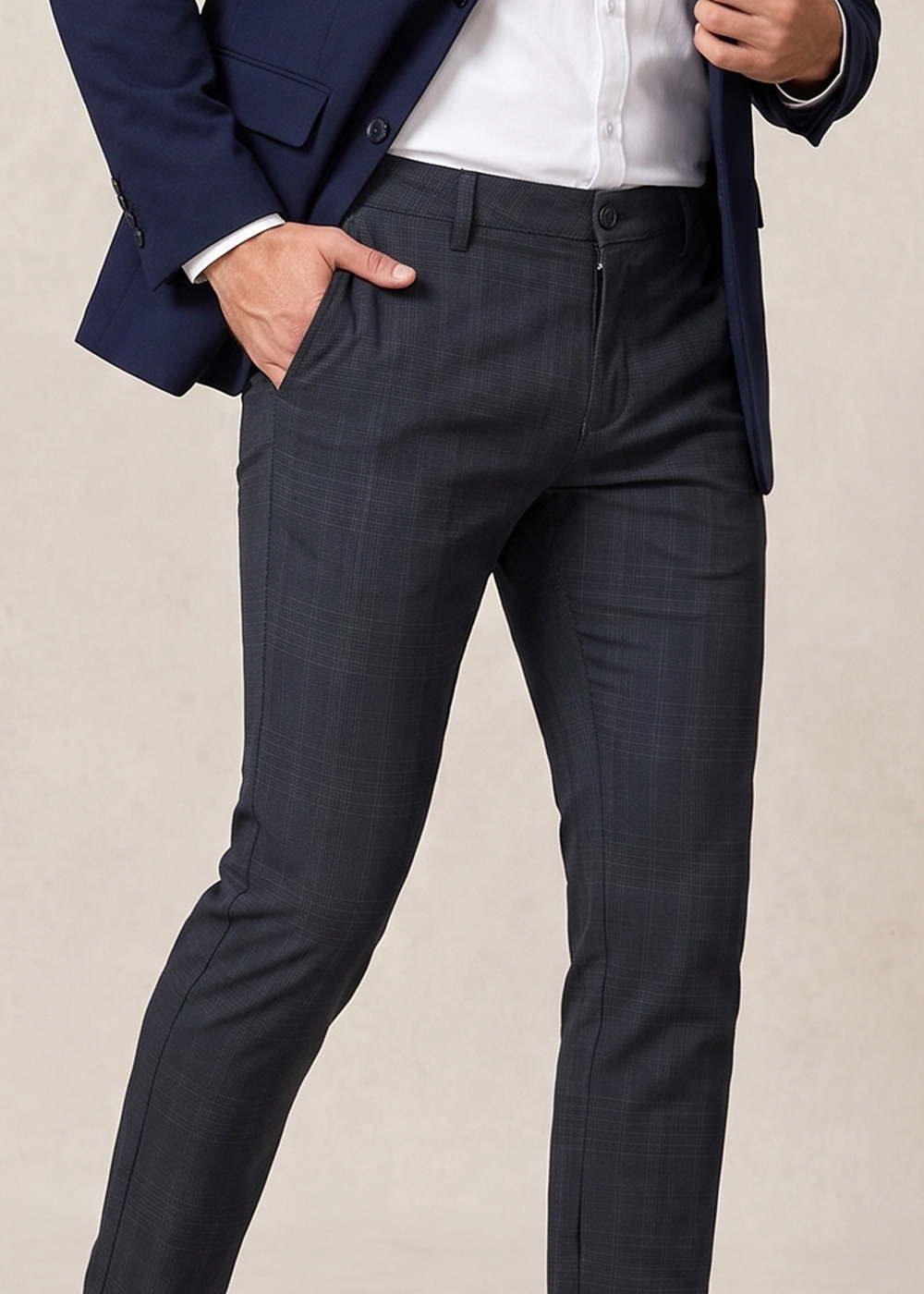 Model wearing navy blazer, white shirt and slim-fit charcoal checked suit trousers, hand in pocket