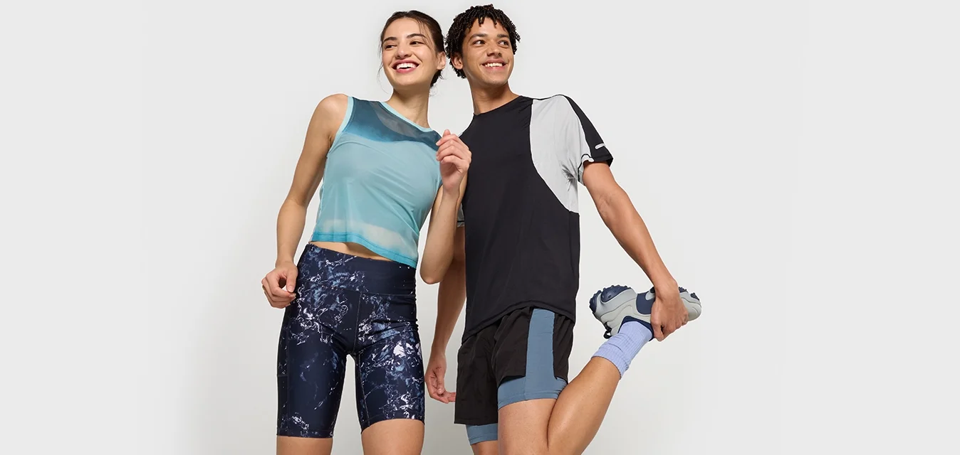Due modelli indossano abbigliamento sportivo: un top senza maniche azzurro chiaro e pantaloni corti a fantasia blu navy per lei; una maglietta nera e grigia con pantaloni corti neri per lui.
