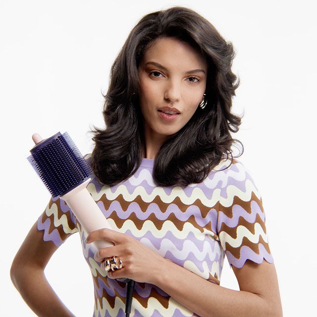 La modella tiene in mano la spazzola per styling Dyson Airsmooth.