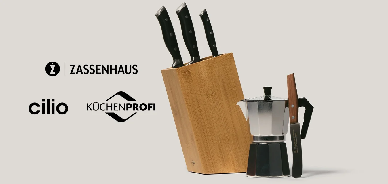 Porta coltelli che contiene tre coltelli con manico nero accanto a una caffettiera moka con manico nero su sfondo beige.