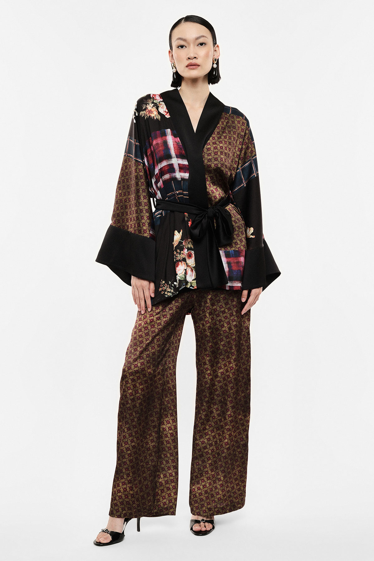 Model wearing patterned kimono-style wrap jacket with sash and matching wide-leg trousers and black heeled sandals