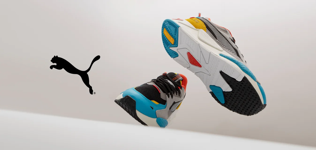 Sneakers atletici colorati che presentano una combinazione di materiali grigi, neri e bianchi, con accenti vivaci in rosso, arancione, giallo e blu.