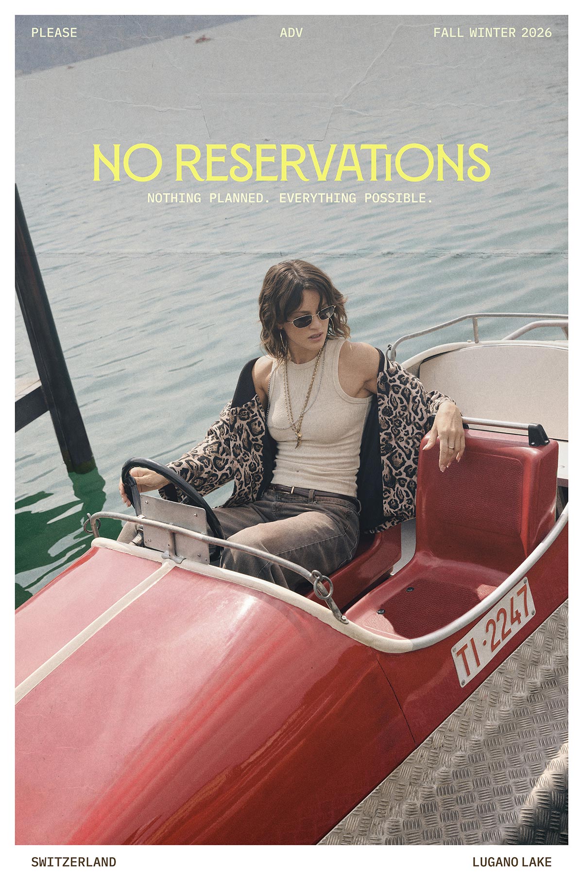 Woman in sunglasses and leopard-print jacket seated in a red pedal boat on Lake Lugano, Switzerland, with 'No Reservations' headline