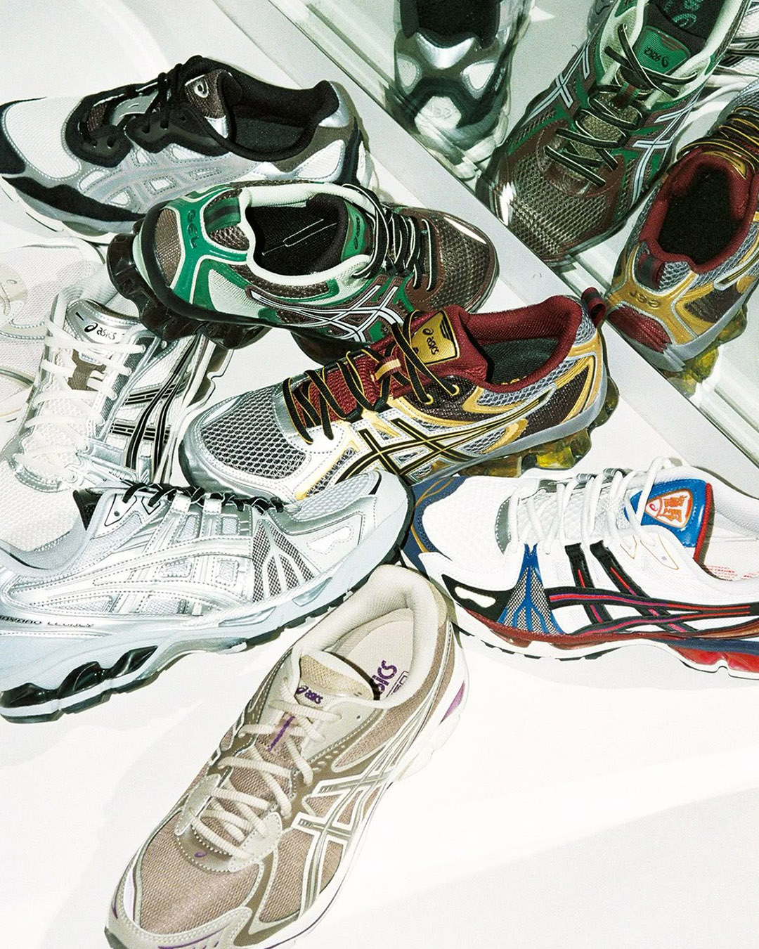 Assortment of colourful ASICS running trainers in various styles and colours arranged on a mirrored surface