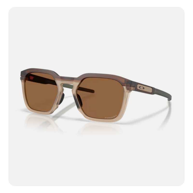 Translucent brown square sunglasses with brown lenses and Oakley logo on grey temples, modern unisex style on white background
