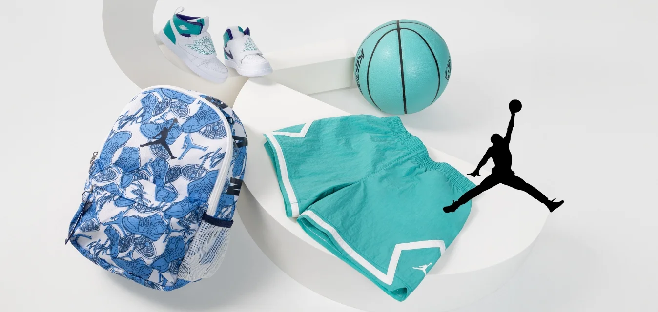 Zaino con motivo floreale blu, pantaloni corto teal, sneakers bianche e un pallone da basket teal su una superficie bianca curva.