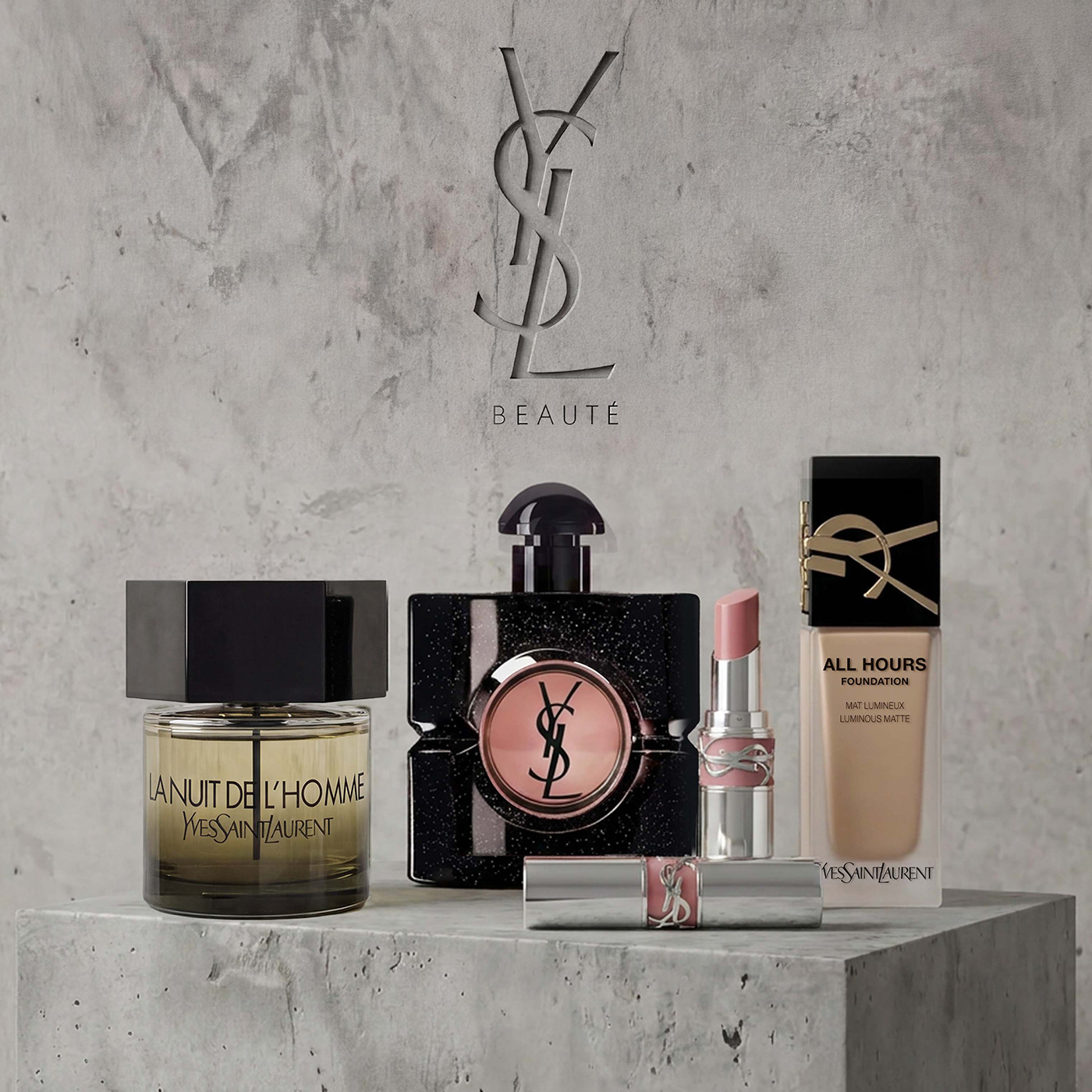 Una selezione di prodotti iconici YSL &mdash; La Nuit de L'Homme, Black Opium, rossetto Loveshine e fondotinta All Hours &mdash; su un piedistallo di cemento.