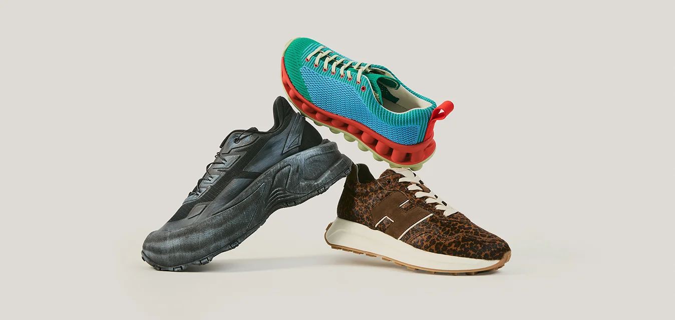 Tre sneaker bilanciate insieme: una nera con suola spessa, una blu con suola rossa e una marrone con stampa leopardata e suola bianca.
