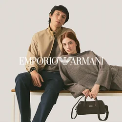 Due giovani posano su una panchina, uno seduto che indossa una giacca beige, l'altro sdraiato in un vestito grigio che tiene una borsa nera.