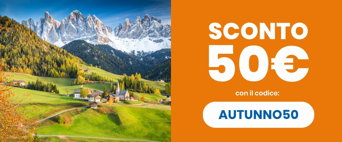Autumn Alpine village with green meadows and snow‑capped Dolomite peaks left; orange panel right showing 'SCONTO 50€' and code AUTUNNO50