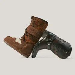 Stivale invernale marrone in pelle scamosciata foderato in pelliccia, appoggiato a uno stivale da cowboy in pelle nera con cuciture e dettagli con fibbia.
