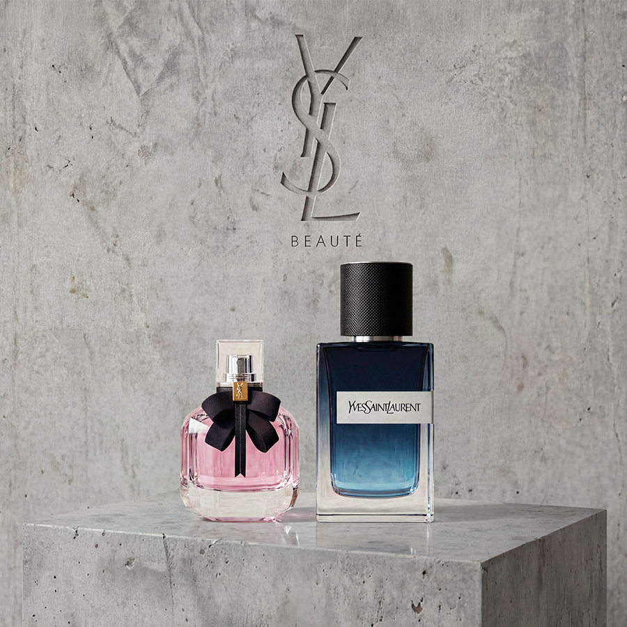 Les flacons des parfums Mon Paris et Y Eau de Parfum d'YSL pr&eacute;sent&eacute;s sur un socle en b&eacute;ton sous un logo grav&eacute;.