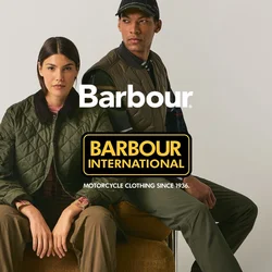 Due persone con abbigliamento outdoor verde siedono e si appoggiano a un cuscino rotondo marrone su uno sfondo beige uniforme.