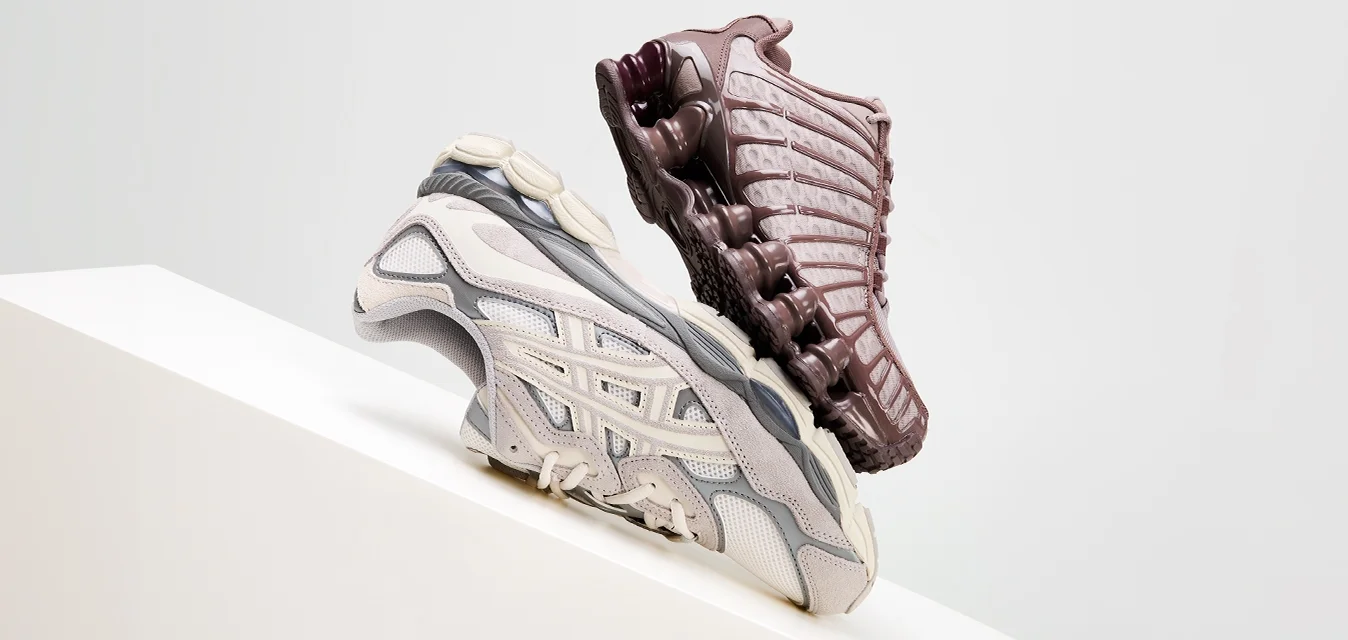 Scarpe da ginnastica atletiche in beige e bordeaux scuro, dotate di materiale in rete, suole testurizzate e elementi di design elaborati, esposte su un piedistallo bianco.