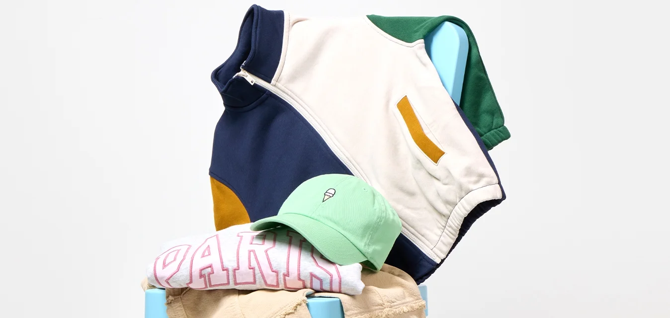 Una sedia blu tiene dei pantaloni beige piegati, una maglietta rosa con la scritta 