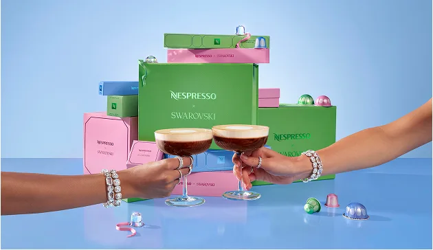 Mani di due modelle che indossano i gioielli Swarovski e tengono due coppe contenenti caffè Nespresso