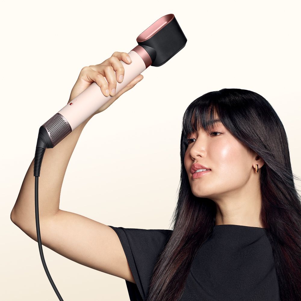 Una modella si asciuga i capelli usando lo styler asciugacapelli Dyson Airwrap Co-anda2x.
