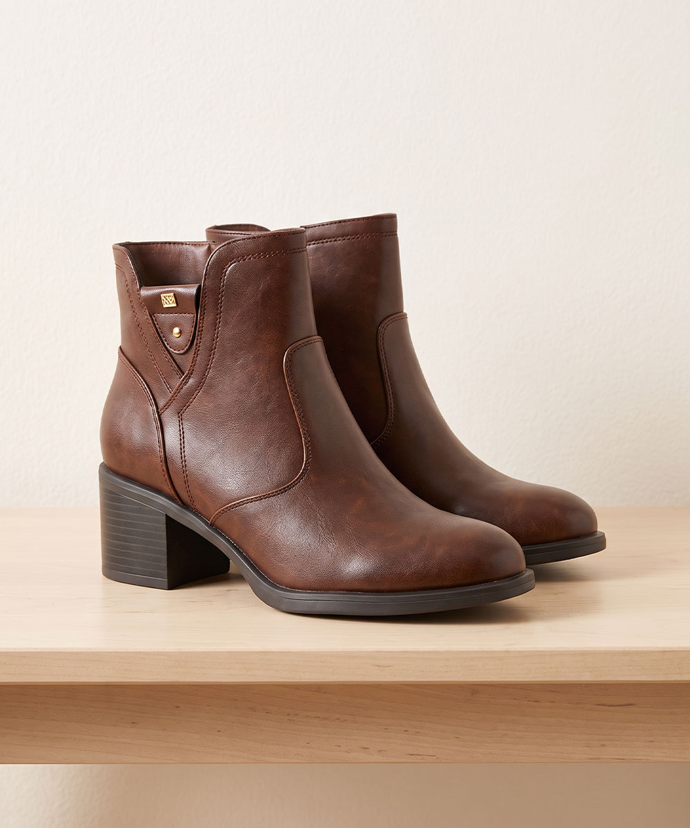 Pair of women's brown leather ankle boots with low stacked block heel displayed on a wooden shelf