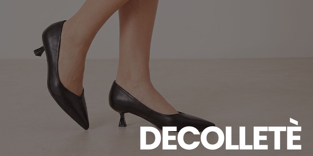 Woman's feet in black leather pointed-toe kitten-heel pumps on neutral floor with 'DECOLLETÈ' text