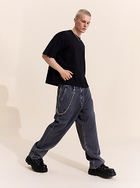 Uomo con T-shirt nera e jeans grigi ampi.