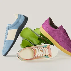 Quattro sneaker colorate in blu, rosa, multicolore e verde disposte in piedi con due bottiglie di vetro verdi su uno sfondo neutro.