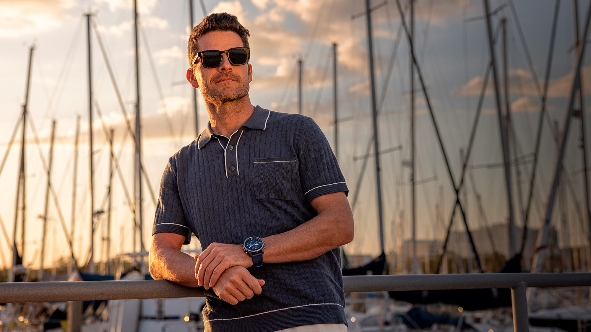 Uomo in banchina con il Garmin Quatix 8 al polso, alberi di barche a vela sullo sfondo