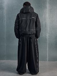 Uomo con giacca nera e pantaloni neri ampi.
