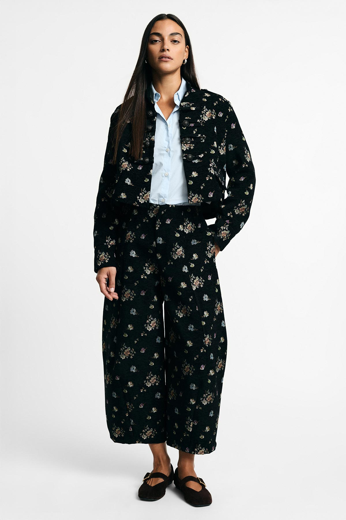 Woman modelling black floral cropped jacket and matching wide-leg trousers, pale blue shirt and black Mary Jane shoes