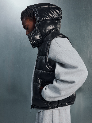 Uomo con gilet imbottito nero e felpa grigia.