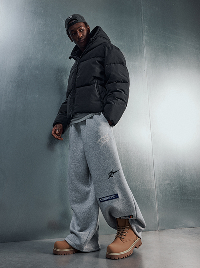 Uomo con piumino nero e pantaloni grigi.