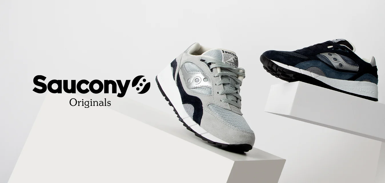 Sneaker in suede grigio e mesh con accenti neri, caratterizzato da una punta arrotondata e suola testurizzata; sneaker blu con design simile sul lato opposto.