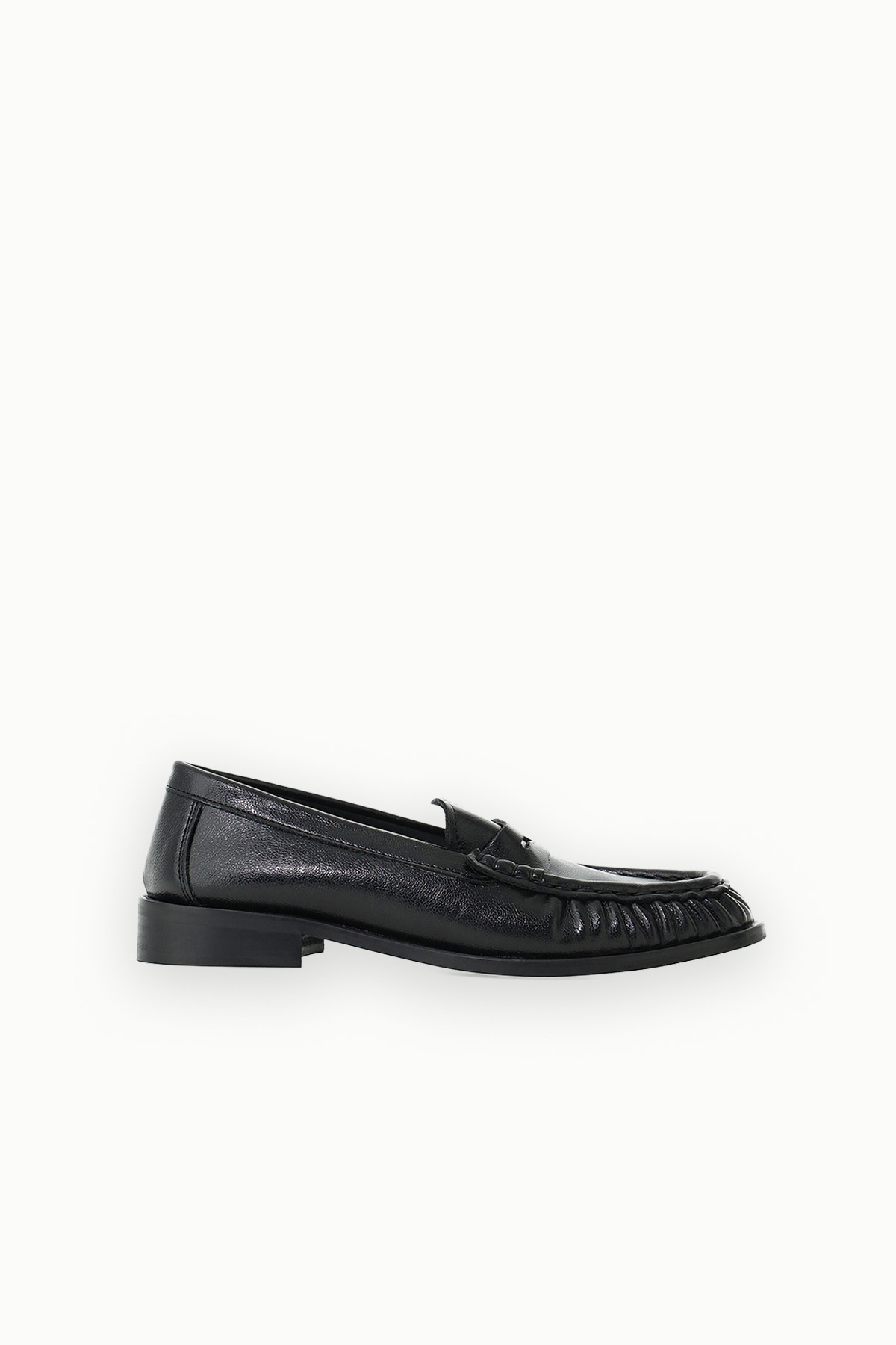 Black leather men's penny loafer with fringe detailing and low heel, side profile on white background