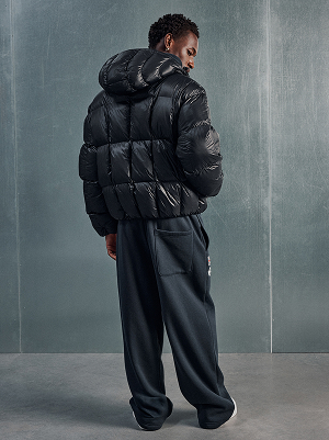 Uomo con piumino nero e pantaloni ampi.