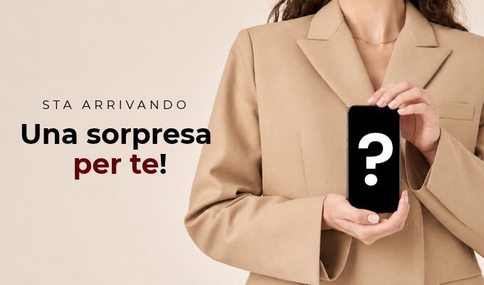 Person in beige blazer holding smartphone with white question mark, promotional Italian text 'Sta arrivando Una sorpresa per te!'