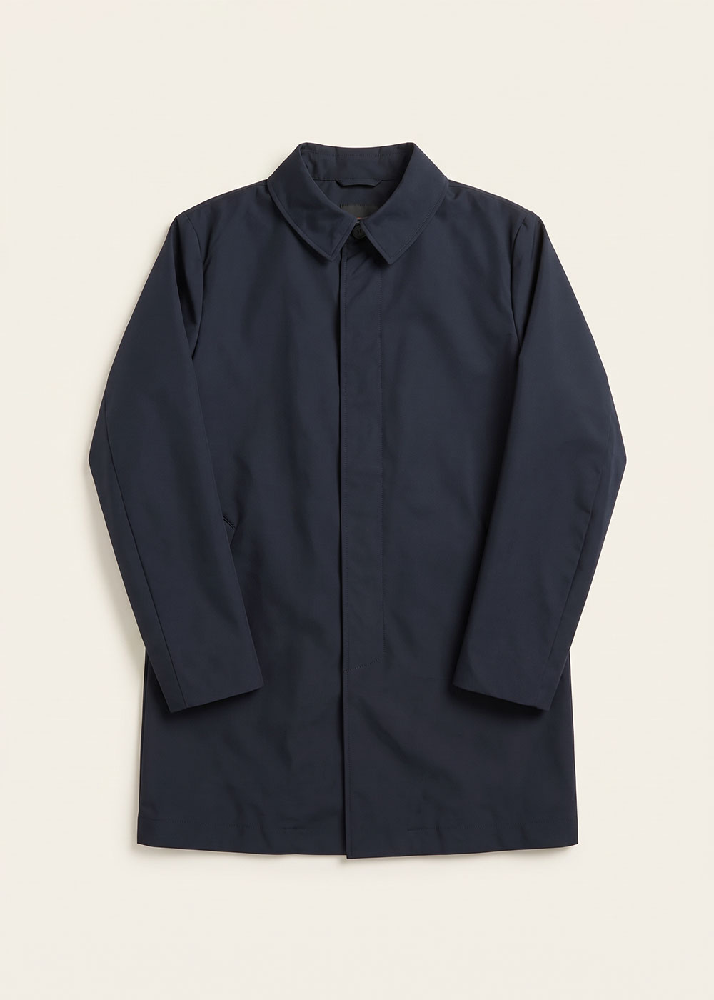 Men's navy single-breasted waterproof coat with concealed button placket and classic collar, long sleeves, flat-lay on cream background