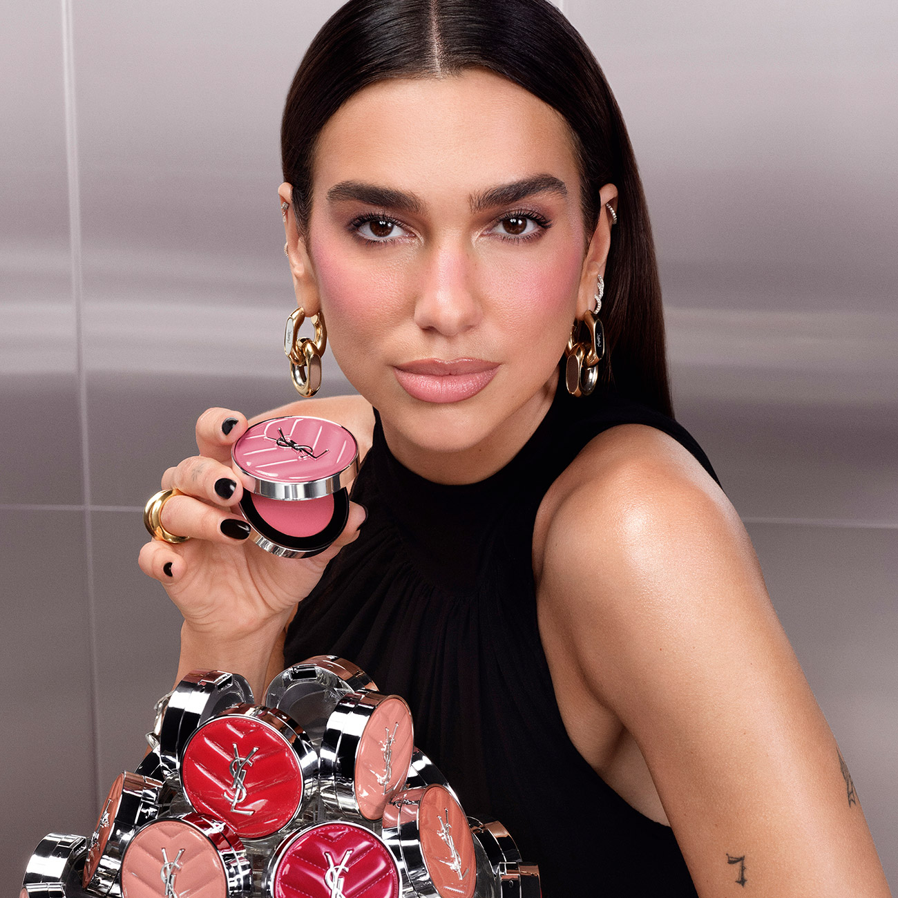 La cantante Dua Lipa con un blush compatto rosa YSL sopra una piramide di varie tonalit&agrave;.