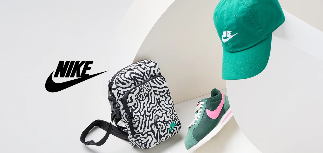 Cappello verde Nike, zaino con motivo bianco e nero, sneakers verdi e rosa e scarpe bianche con accenti verdi, disposti in modo dinamico su una superficie bianca.