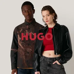 Due modelli si trovano di fronte a uno sfondo neutro. Uno indossa una camicia a fantasia marrone e jeans blu, l'altro una giacca cropped nera e pantaloni grigi.