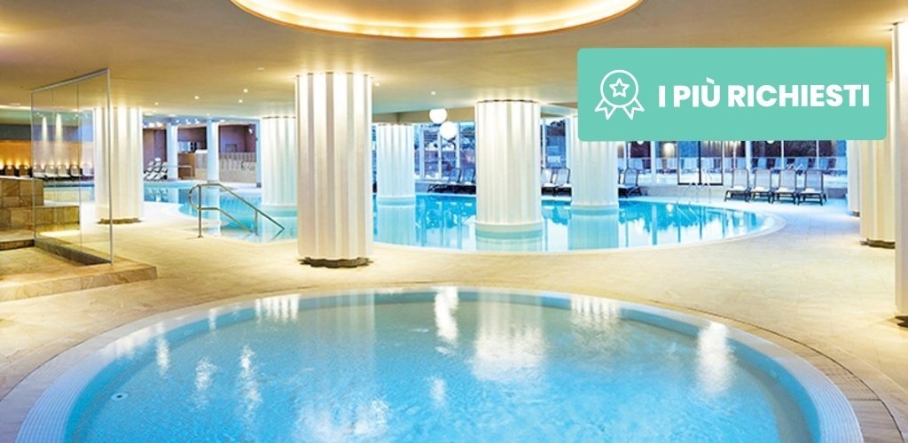 Luxury indoor spa with circular heated pools, white columns and loungers in a bright modern hotel wellness area