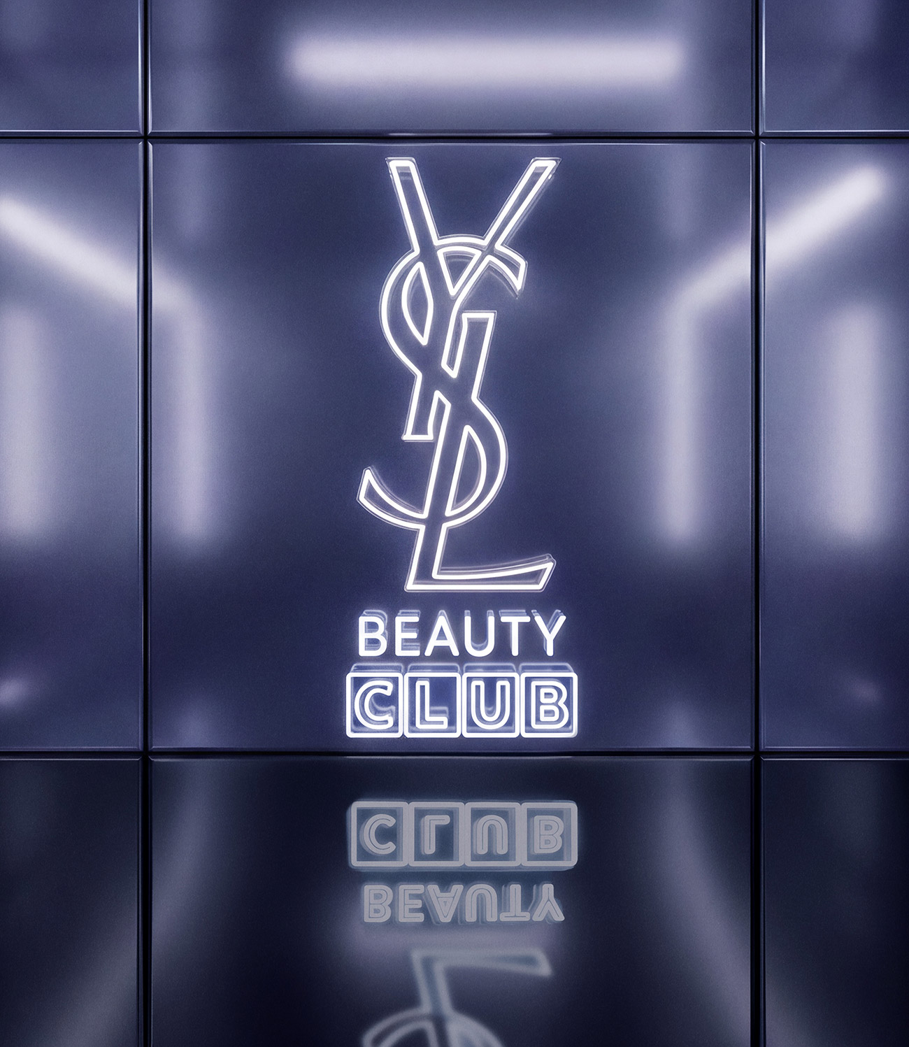 Un logo YSL Beauty Club al neon bianco luminoso su una parete metallica viola riflettente.