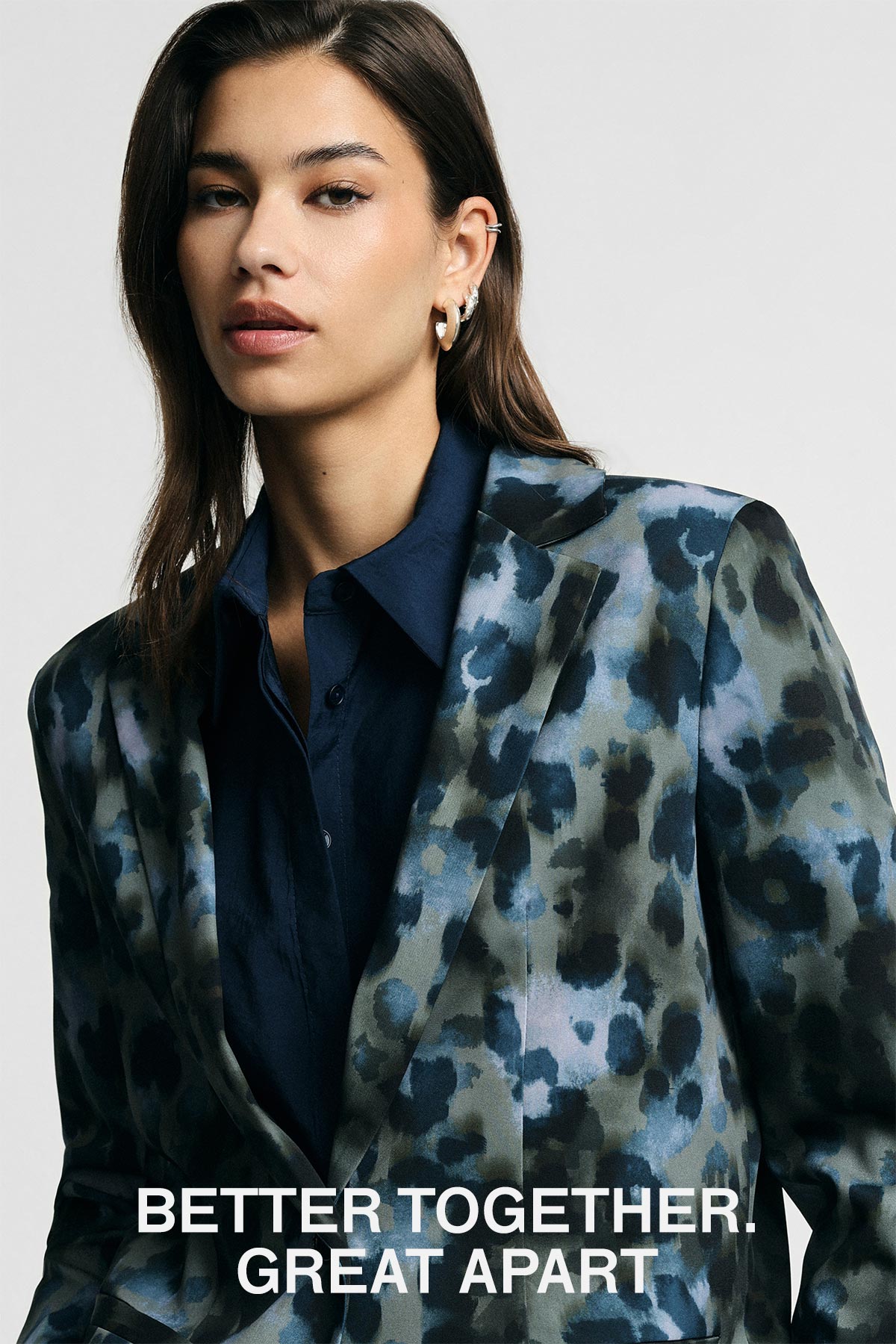 Head-and-torso portrait of a woman in a blue patterned blazer and navy shirt with hoop earrings, slogan 'BETTER TOGETHER. GREAT APART'.