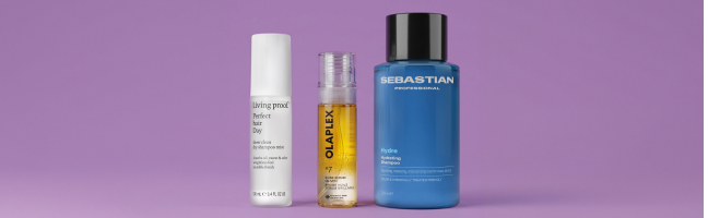 Tre prodotti per la cura e lo styling dei capelli in tubetti e flaconi su uno sfondo viola.
