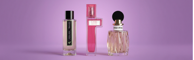Tre diversi flaconi di profumo su uno sfondo viola.