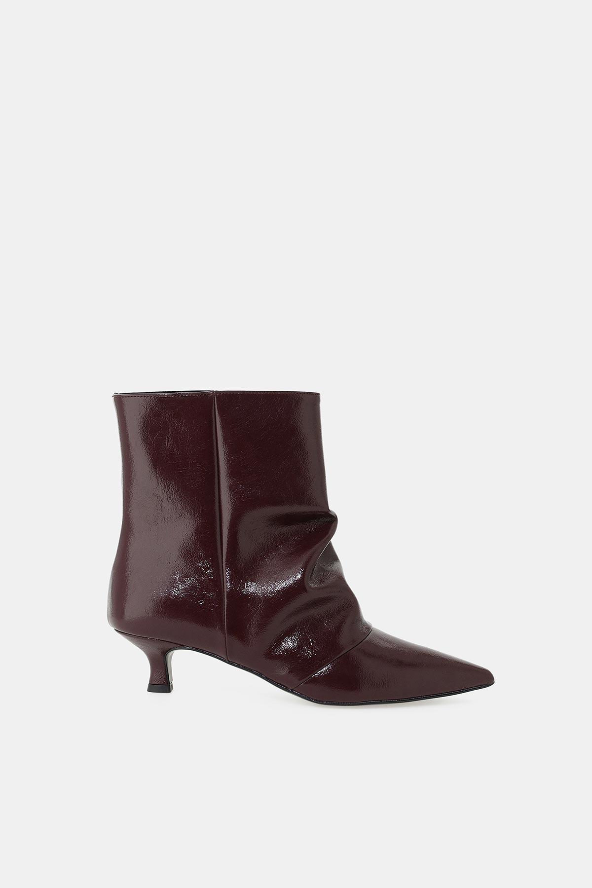 Burgundy patent-leather slouchy ankle boot with pointed toe and low kitten heel, side view on white background