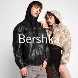 Giacca di pelle nera con dettagli in frange, pantaloni grigi con catena laterale e un crop hoodie mimetico marrone chiaro sopra una gonna in rete nera.